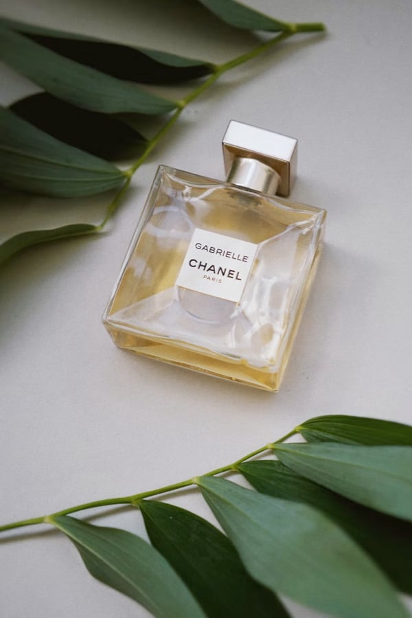 An image of a perfume bottle, surrounded by leaves.